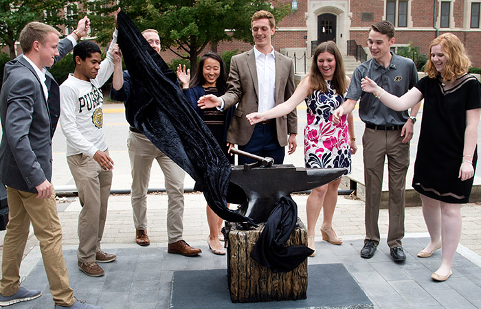 students unveiling a new anvil sculpture on campus 