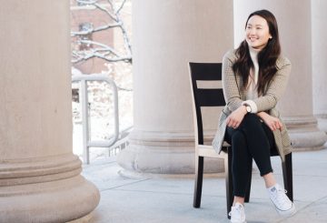 Shannon Kang sitting on a chair next to pillars